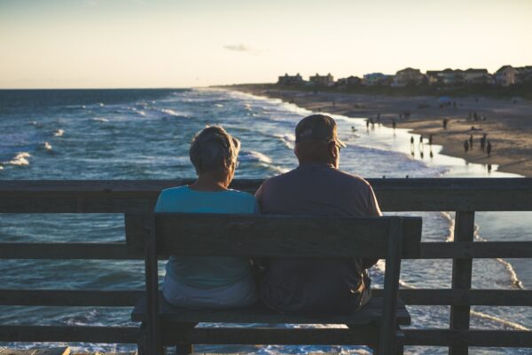 man and woman sitting on bench in front of beach